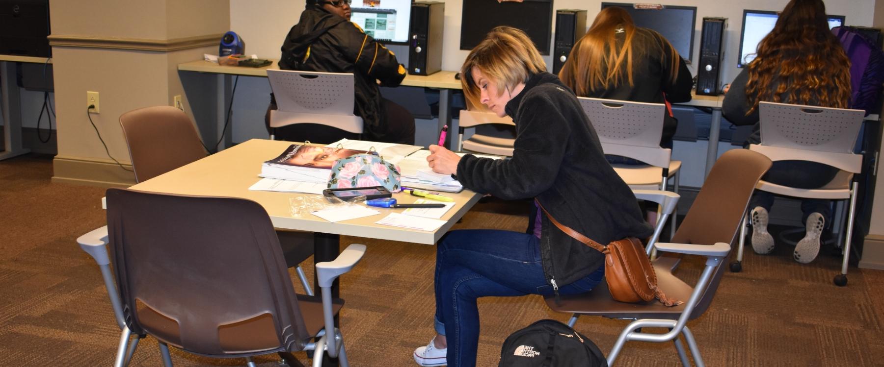 学生在计算机实验室里在课本上做笔记